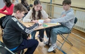 Uczniowie siedzący przy stolikach rowiązują zadania konkursowe